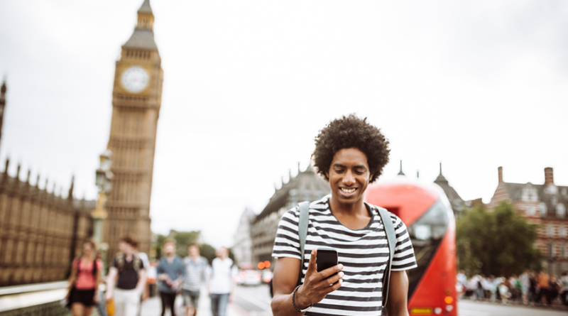 Na imagem, jovem com o celular na cidade de Londres.